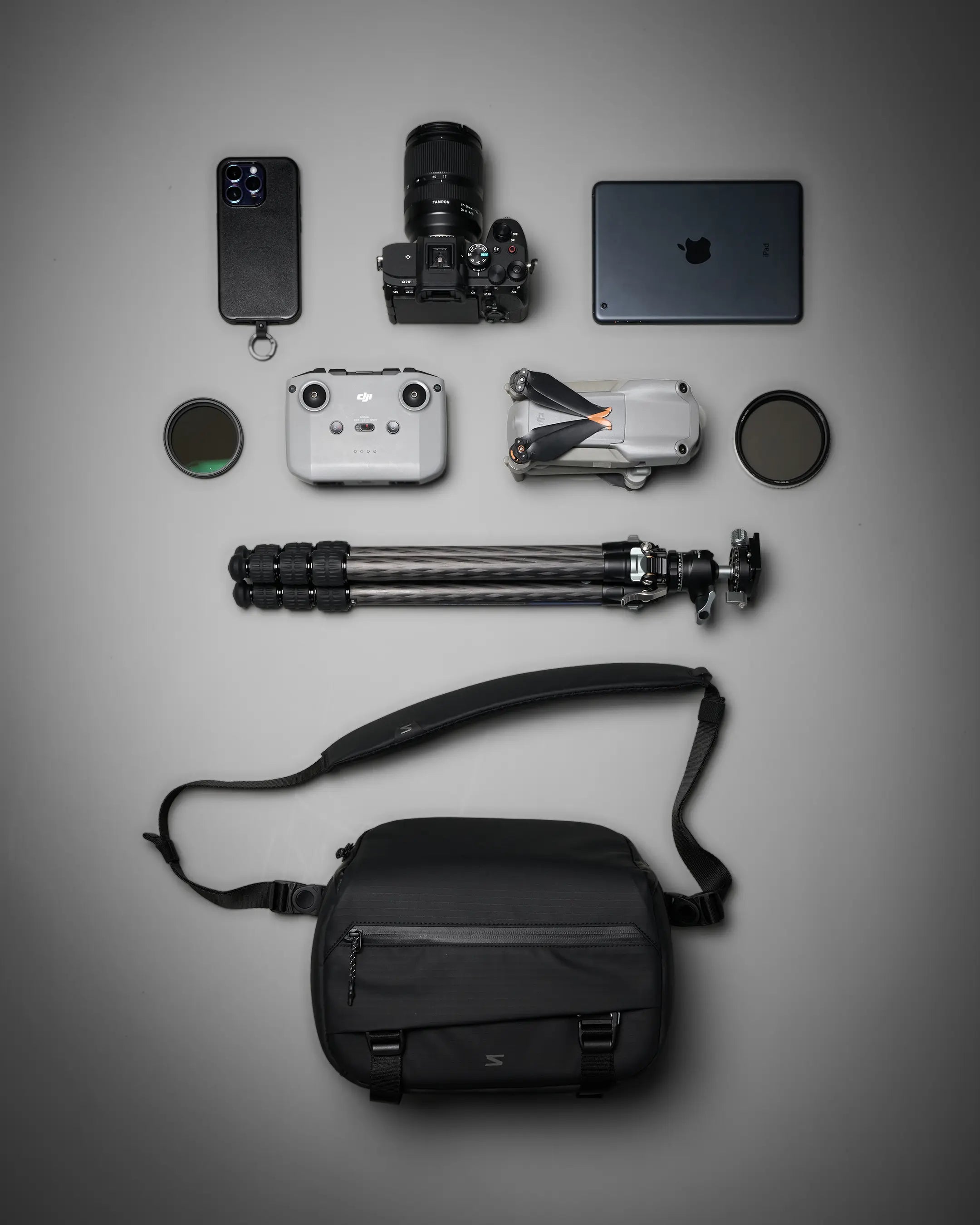 Collection of photography equipment including a camera, phone, laptop, and accessories on a gray background.