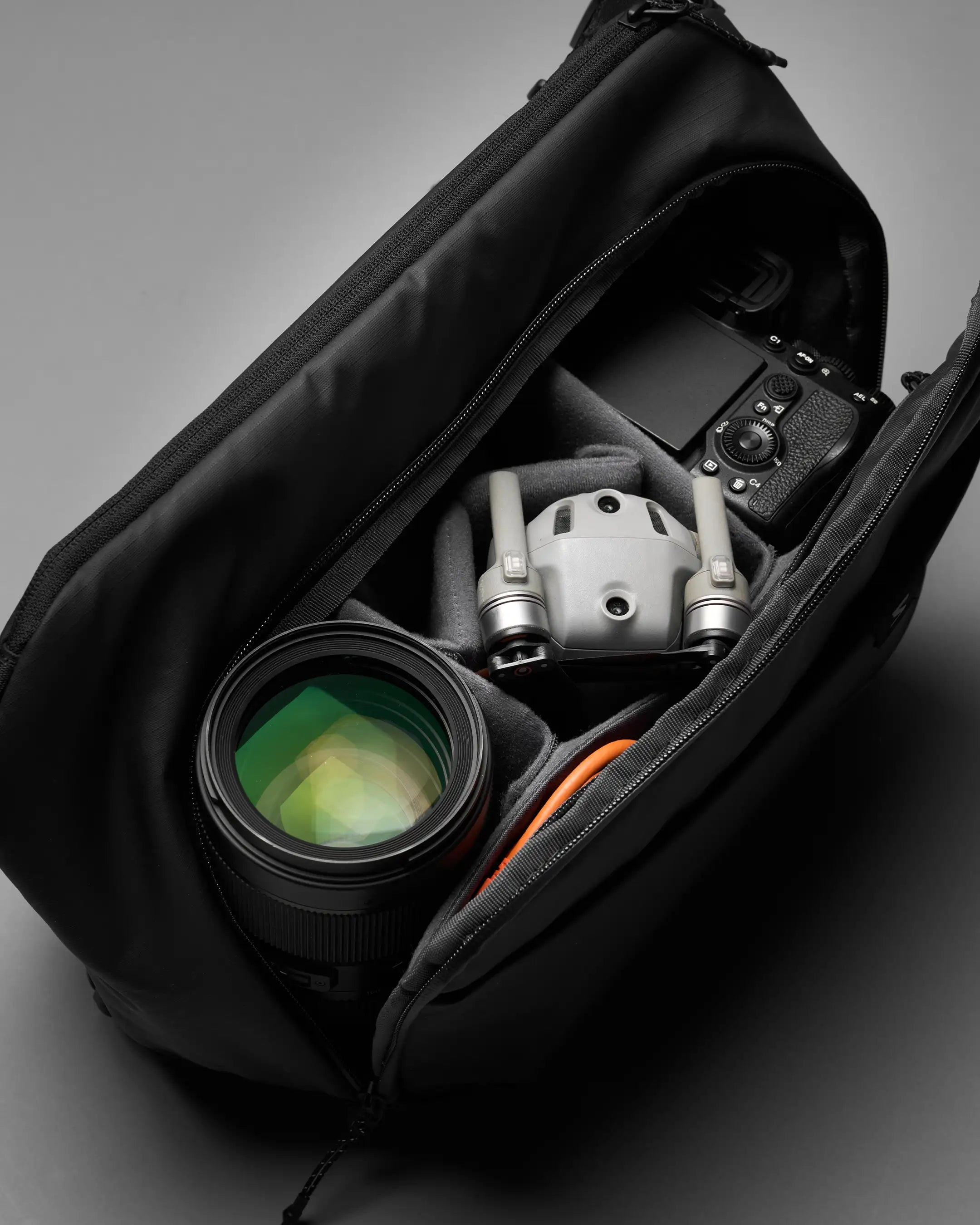 Camera and lens inside an open black bag on a gray background