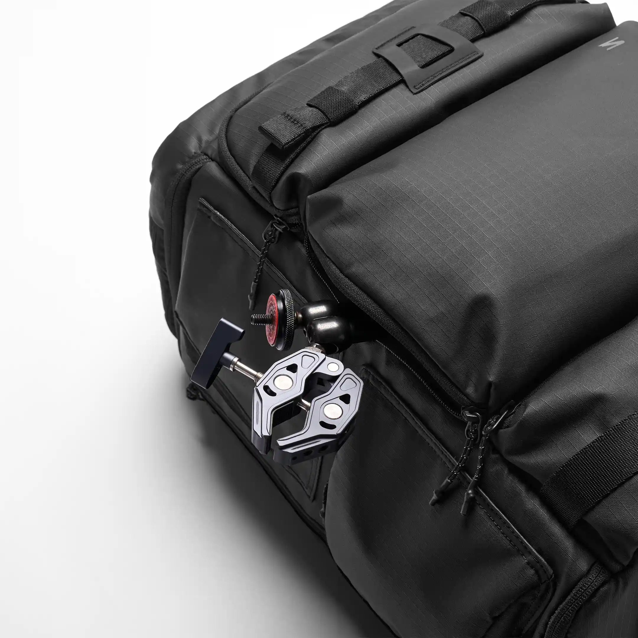 Black backpack with a metal clip attached on a white background