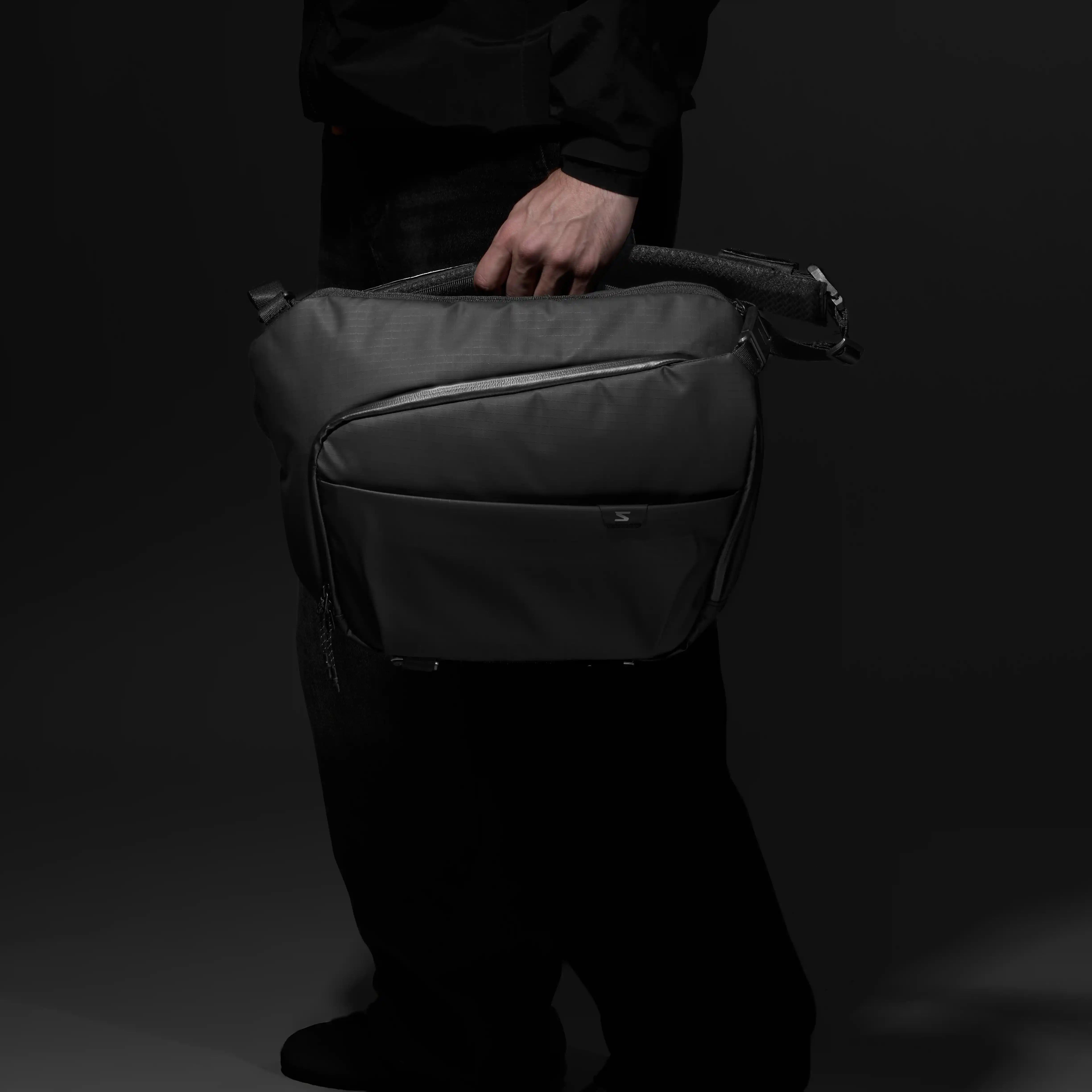 Person holding sling bag with one hand
