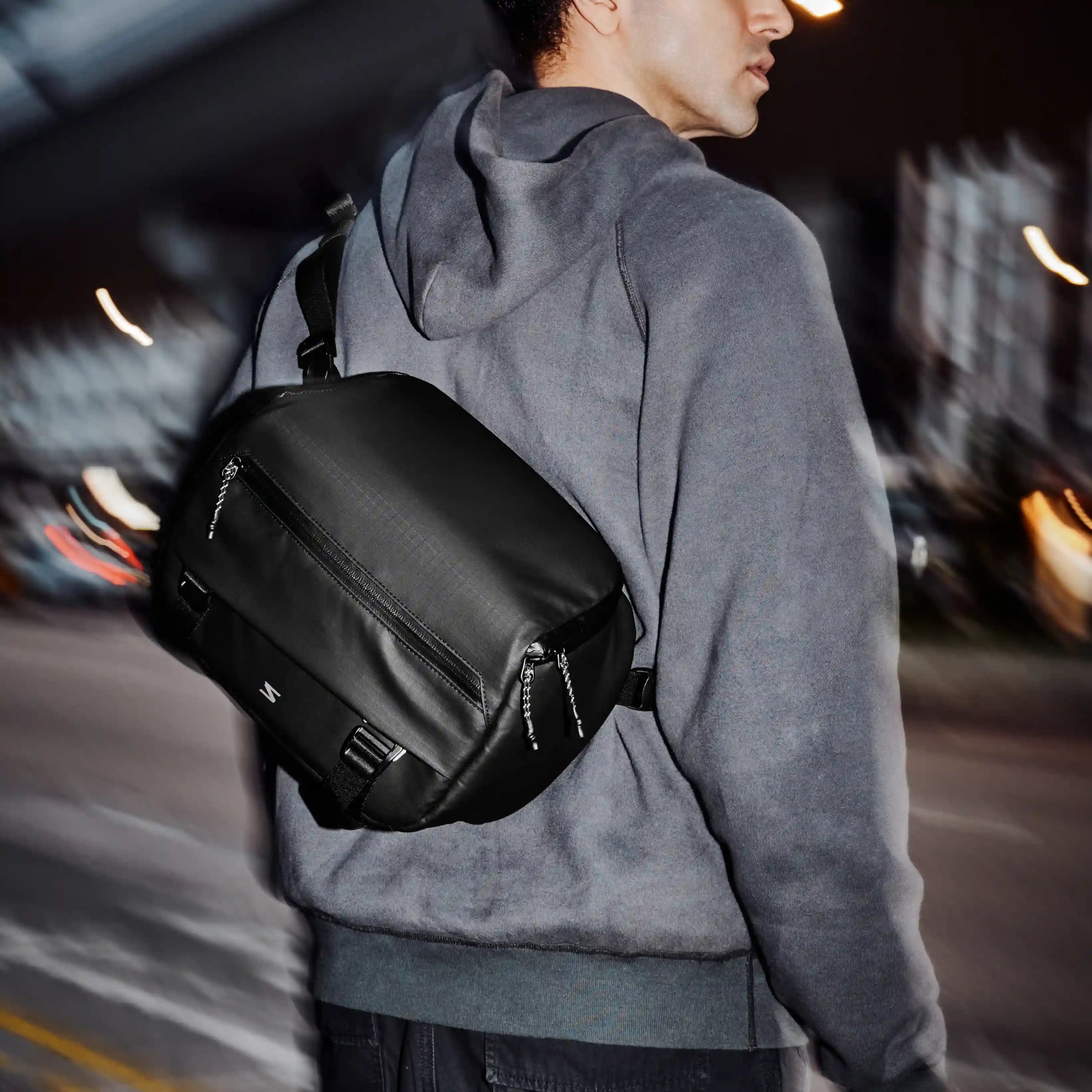 Person wearing a black backpack on a street at night