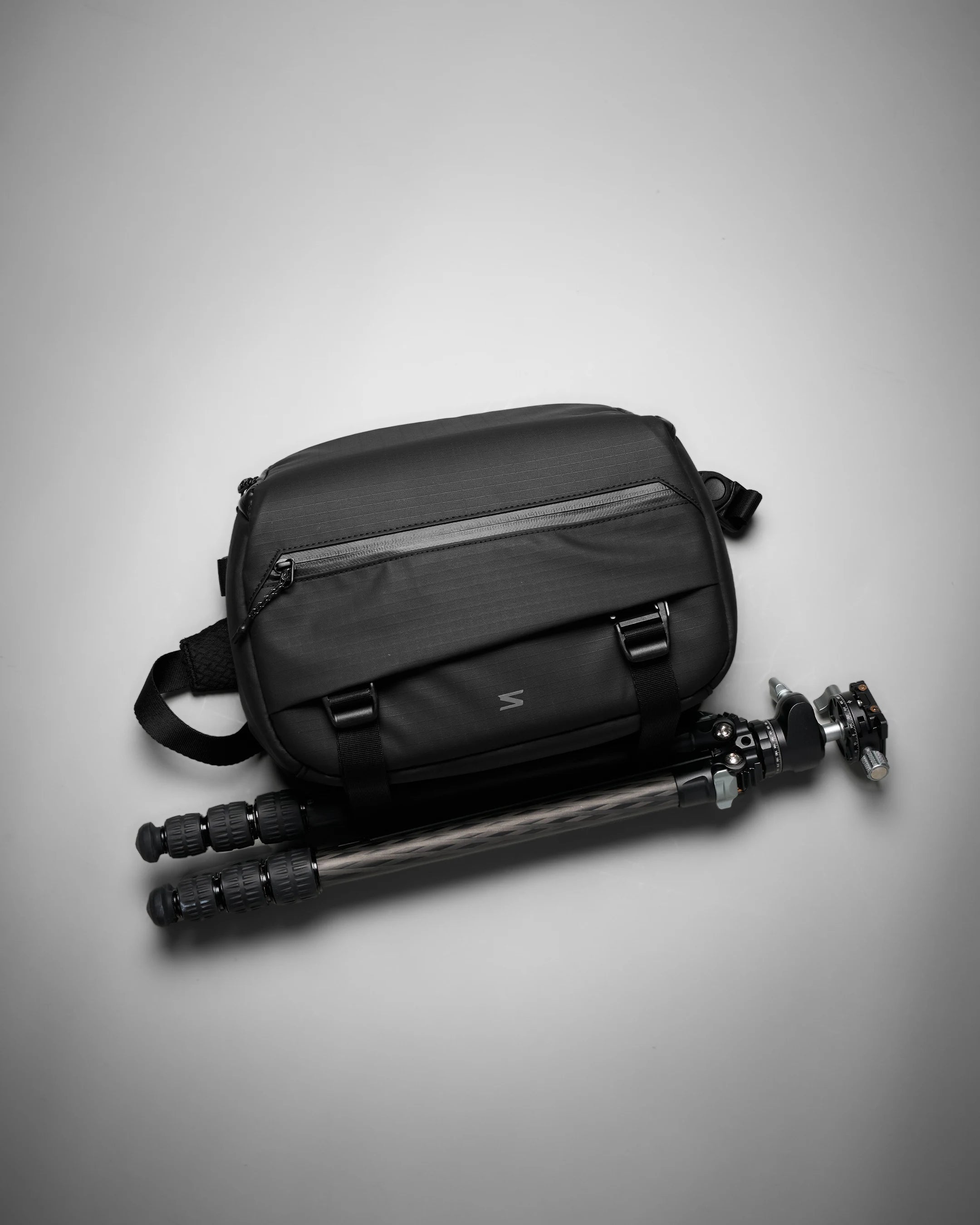 Black camera bag with a tripod on a gray background