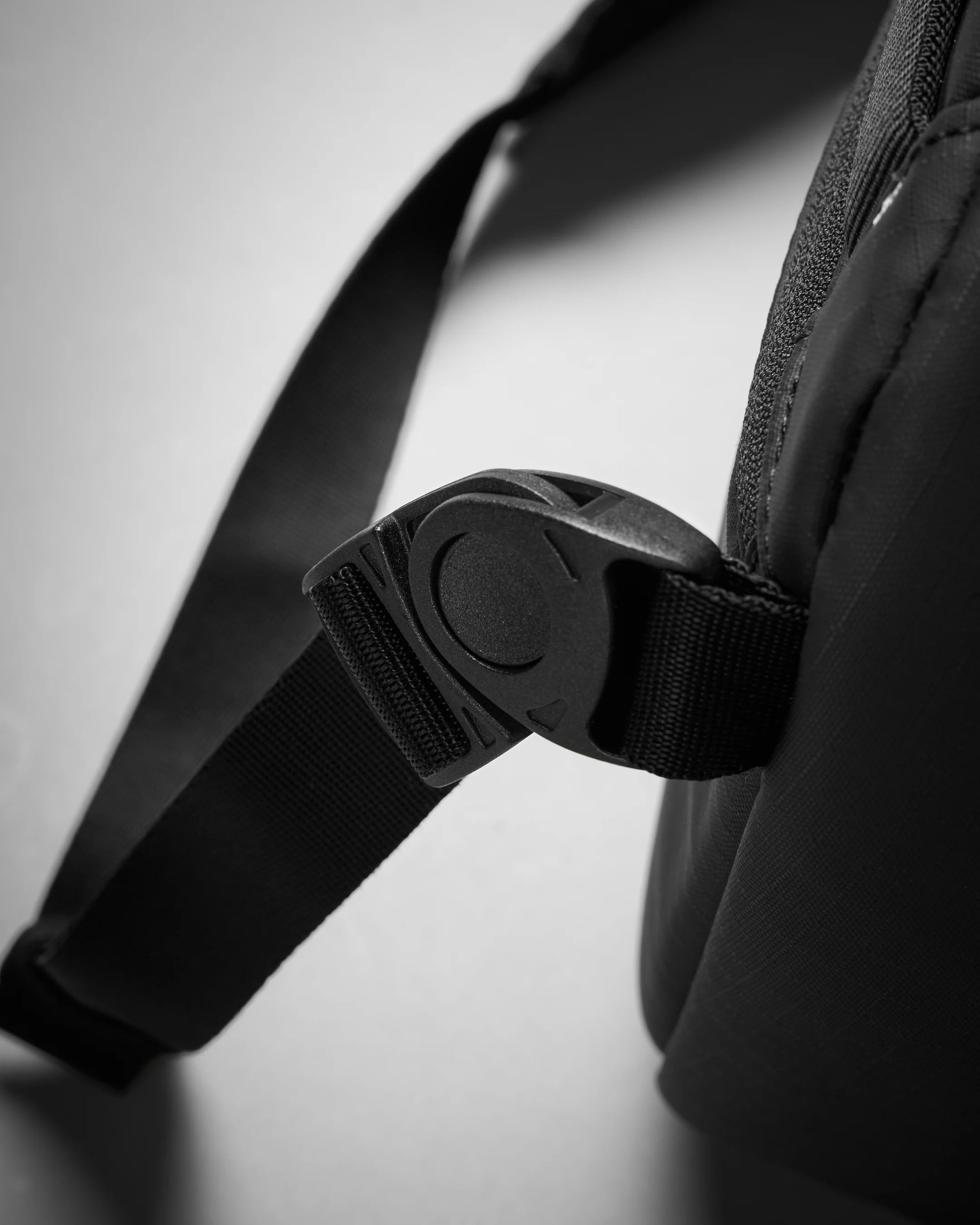 Close-up of a black strap with a buckle on a light gray background