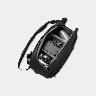 Black camera bag with a camera inside on a light gray background