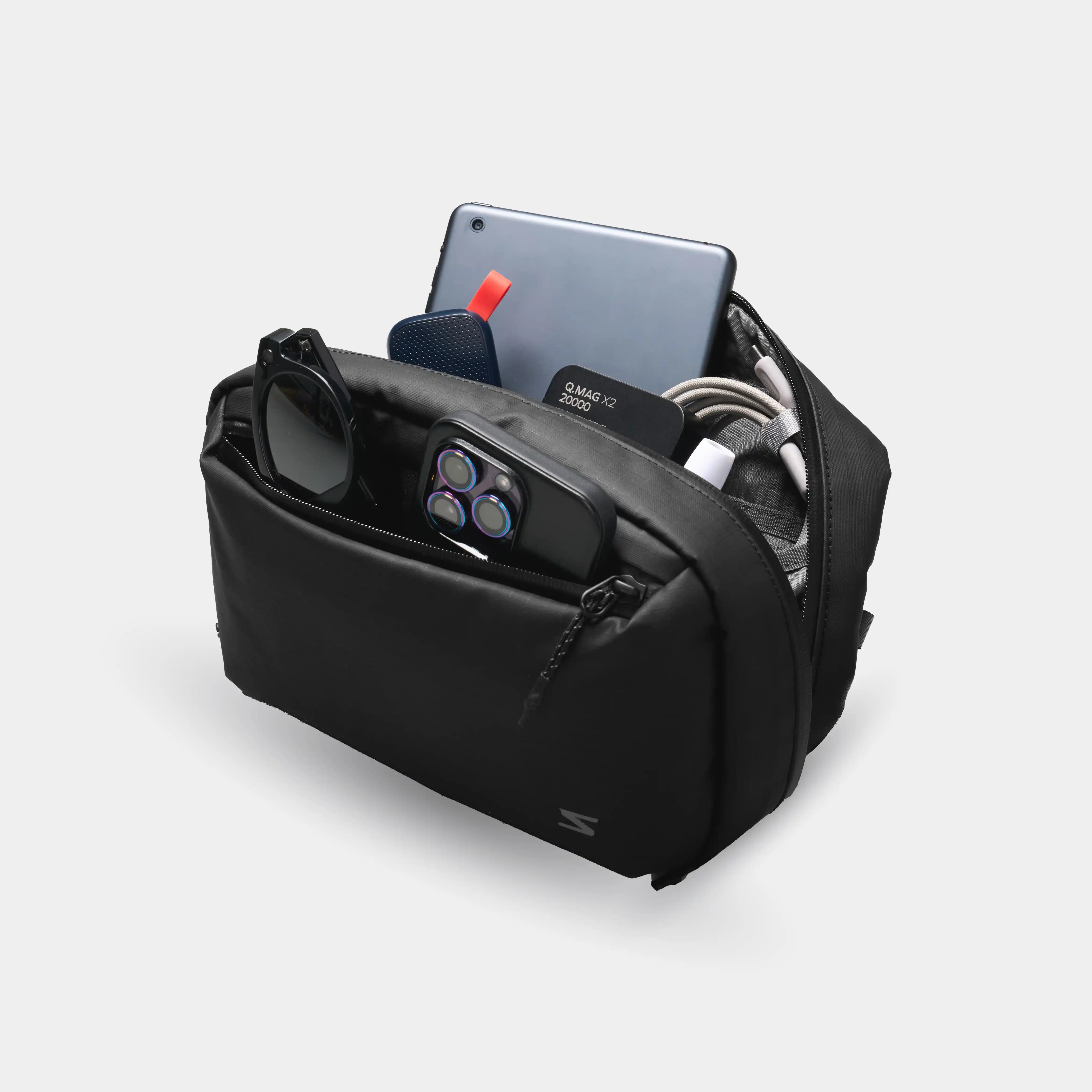 Black travel organizer with electronic devices on a light gray background
