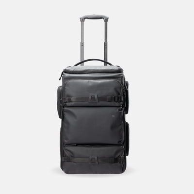 A black rolling duffel bag with an extended telescoping handle, shown from the front against a light gray studio background.