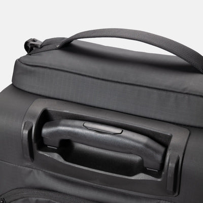 Close-up of a dark gray soft-sided bag with a top handle and a recessed telescoping handle on the front, shown against a light gray background.