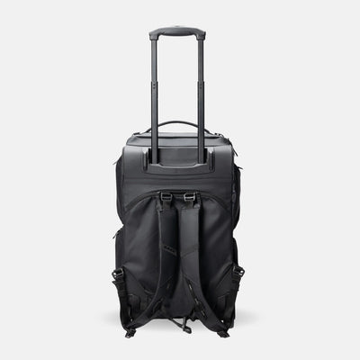 A black rolling duffel bag with an extended telescoping handle, shown from the back against a light gray studio background.