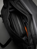 Close-up of a black backpack with orange accents on a gray background