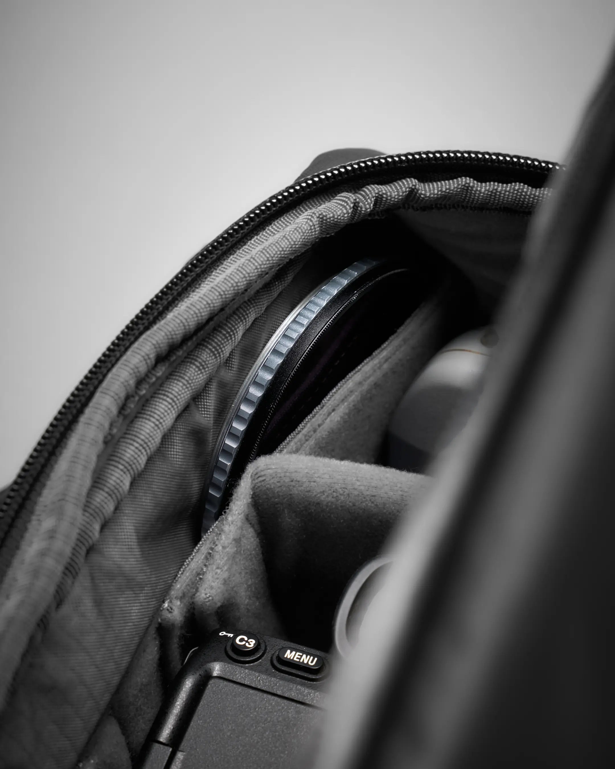 Camera lens and accessories inside a bag with a neutral background