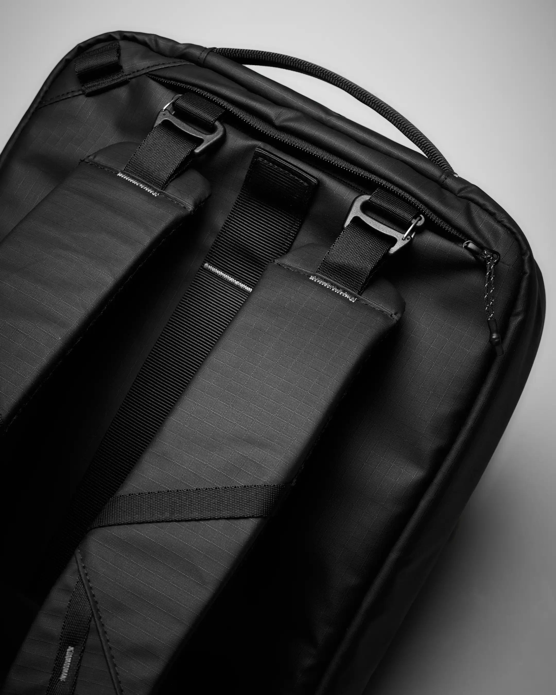Close-up of a black backpack with straps on a gray background