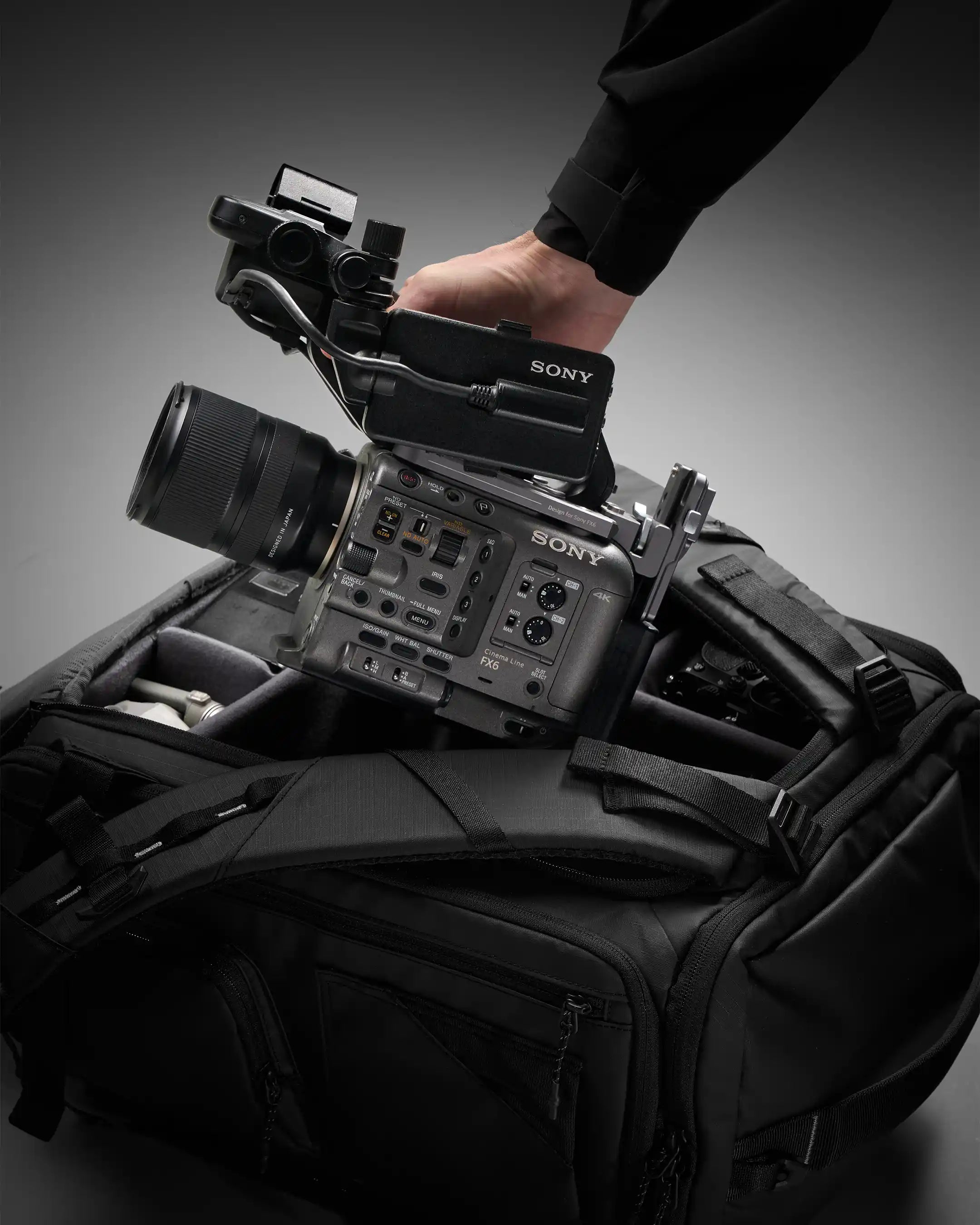 Sony video camera on top of a black backpack with a gray background
