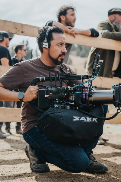 Man operating a camera on a film set with SAKK camera saddle