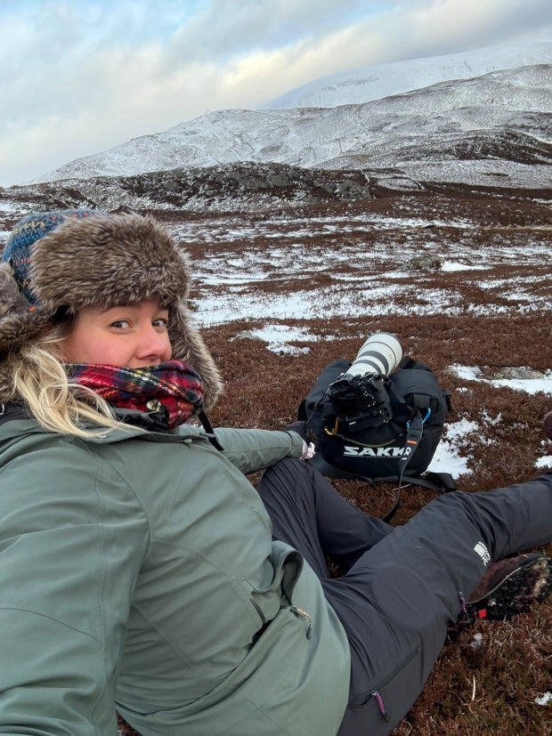Person sitting outdoors in a snowy landscape with mountains in the background