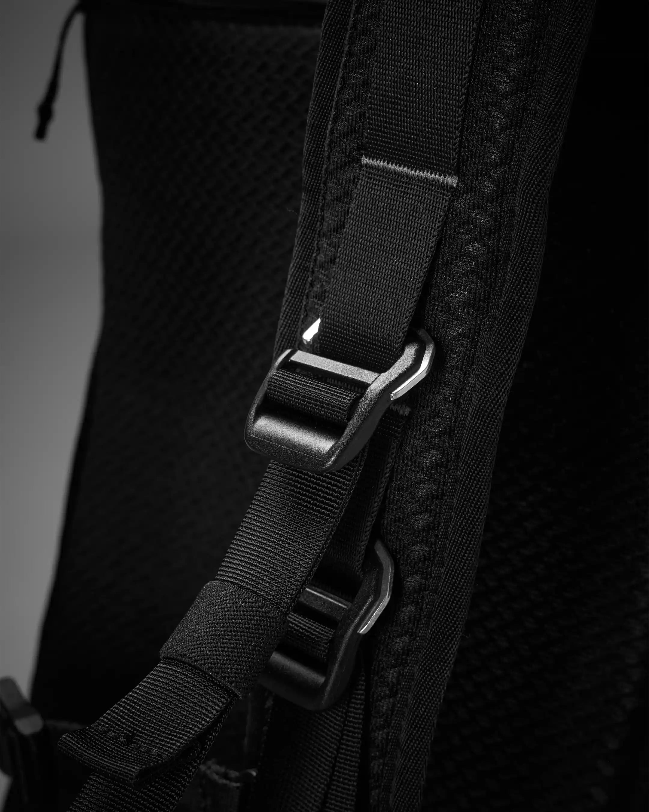 Close-up of a black backpack strap with a buckle on a dark background