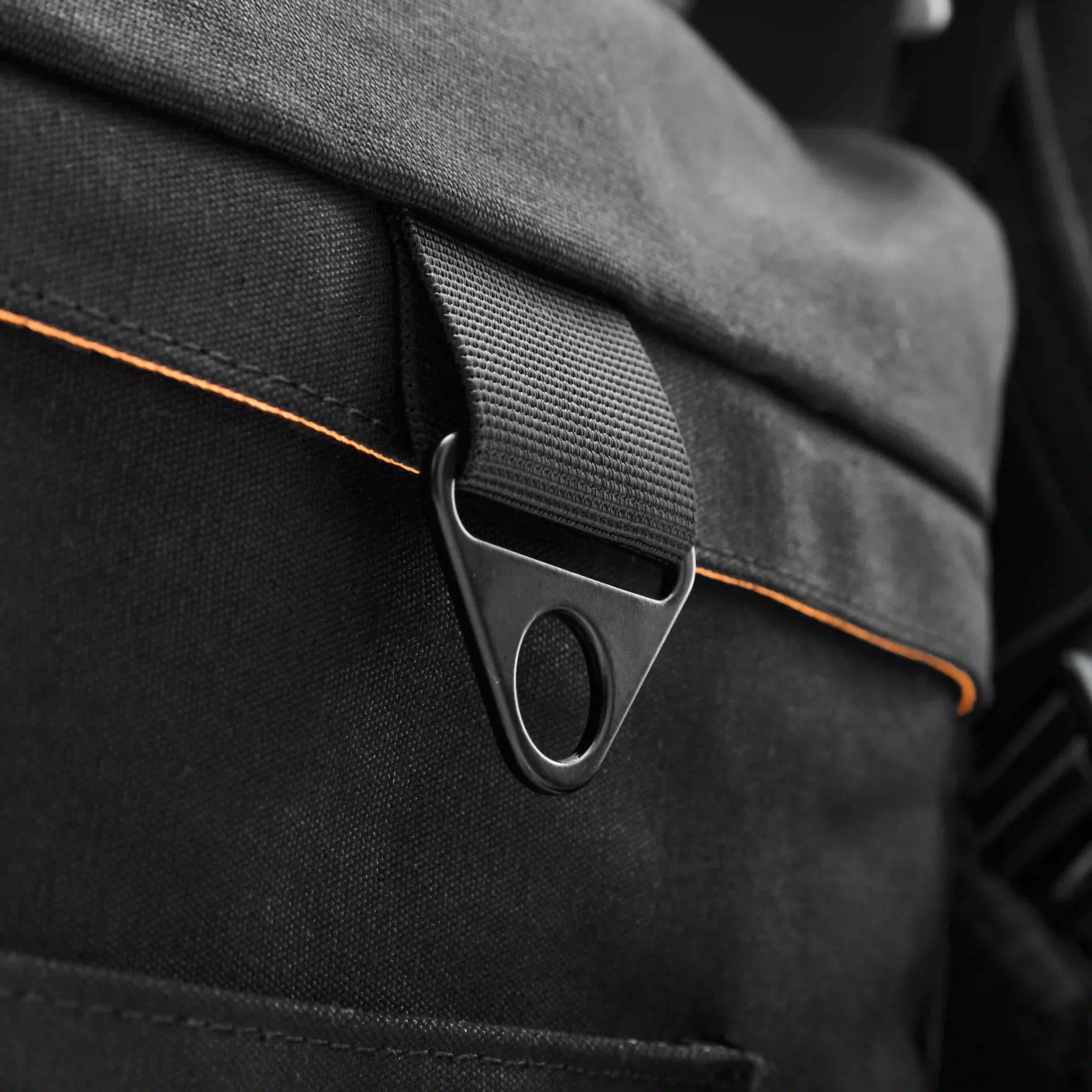Close-up of a black bag with a strap and buckle detail.