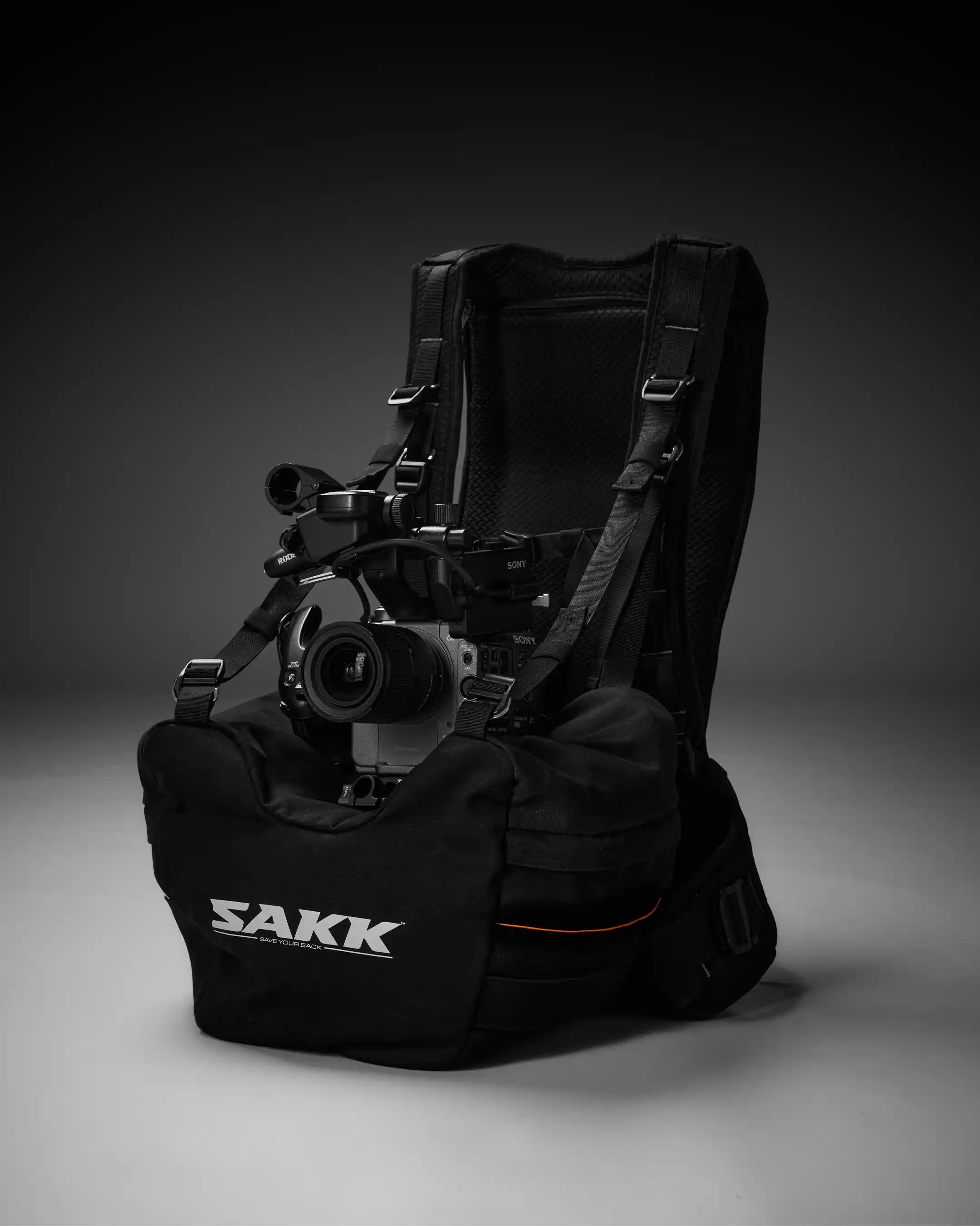 Black backpack with camera equipment on a gray background, featuring the brand 'SAKK'.