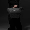 Person holding sling bag with one hand 