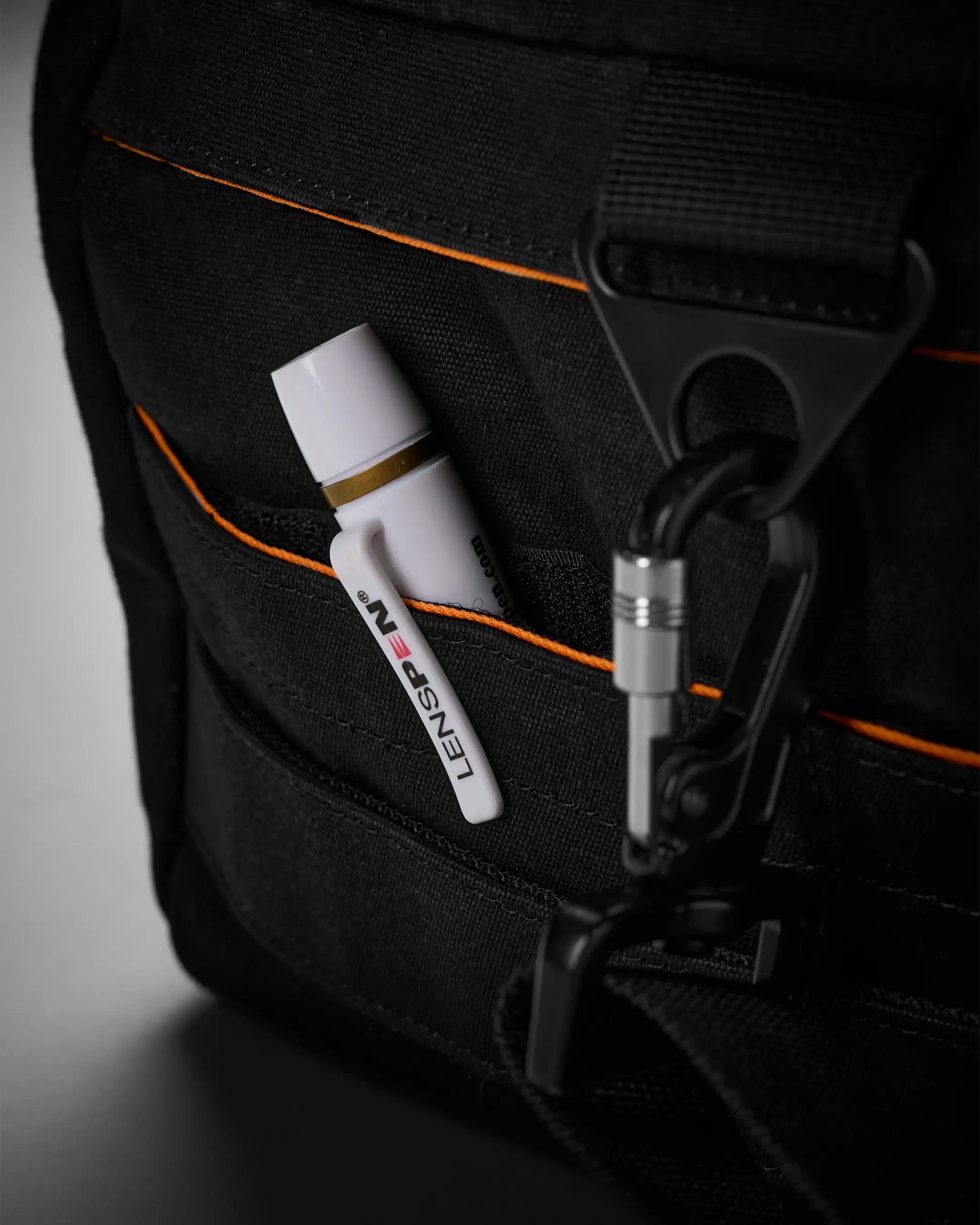 Black bag with a white and gold pen and black strap clip on a gray background