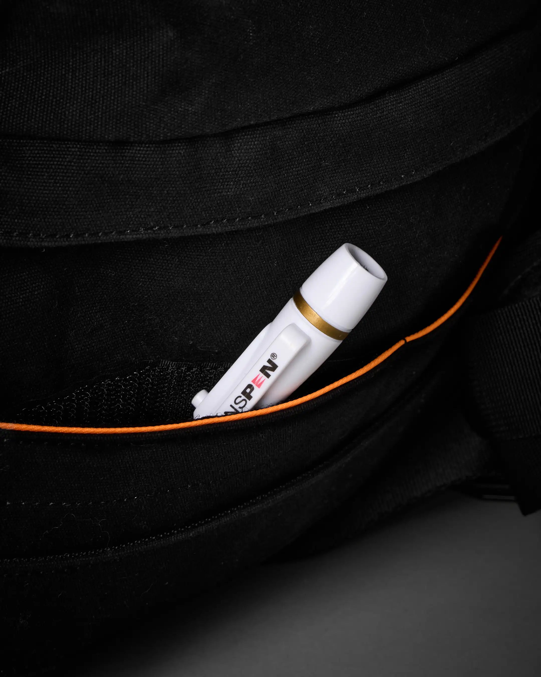 White marker with orange cap peeking out from a black pocket