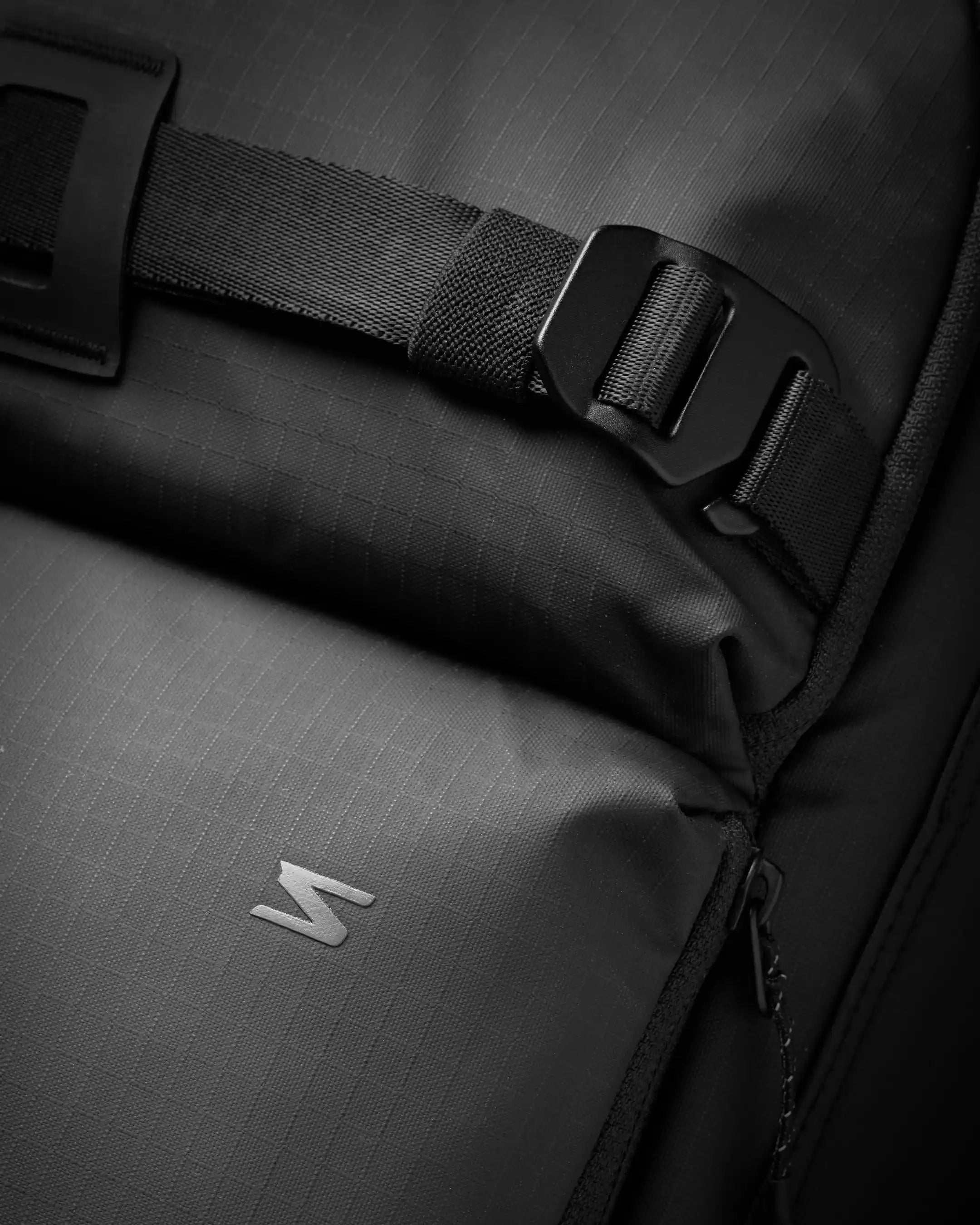 Close-up of a black backpack with a brand logo on a dark background