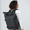 Person wearing a black backpack against a light gray background