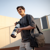 Sling-style camera bag with crossbody strap and laptop fit