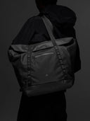 Person wearing a black toter bag against a dark background