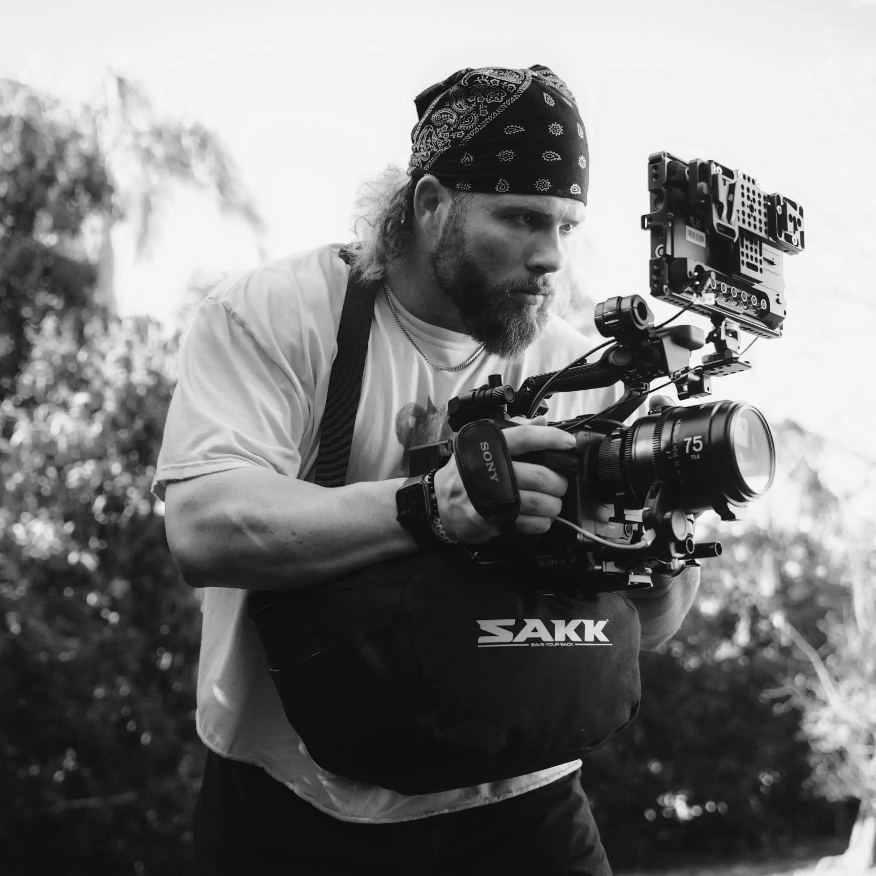 Person holding a camera with 'SAKK' branding outdoors