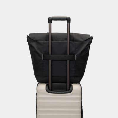 Travel-ready tote bag for creators, slipped onto carry-on luggage handle for easy mobility.