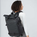 Person wearing a black backpack on a light gray background