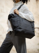 Tote bag packed for a weekend trip with laptop, camera, and change of clothes.
