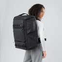 Person wearing a large gray backpack on a plain background